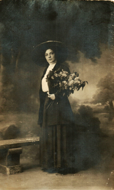 Madeleine. Commentaire de l'intéressée : "ce n'est que sur cette carte qui doit être de 1909 que je porte des lilas. Mon costume était bleu marine et il a contribué à séduire Peya [Aristide]. On ne le dirait pas."